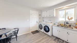 Washroom with a sink, independent washer and dryer, light wood-type flooring, and recessed lighting