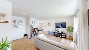 Living room featuring light colored carpet, baseboards, visible vents, and recessed lighting