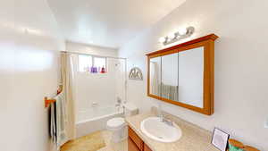 Full bath featuring tile patterned flooring, toilet, shower / tub combo, and vanity