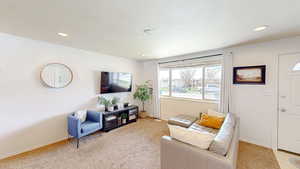 Living room with recessed lighting, light colored carpet, and baseboards