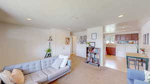 Living room featuring washer and clothes dryer, recessed lighting, and light colored carpet