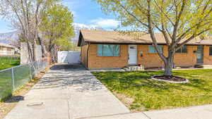 View of front facade with brick siding, a mountain view, fence, and driveway