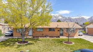 Ranch-style house with a mountain view, driveway, a front lawn, and brick siding