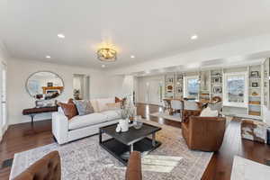 Living area with recessed lighting, wood-type flooring, a notable chandelier, and crown molding