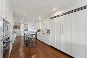 Kitchen with white cabinetry, appliances with stainless steel finishes, recessed lighting, and dark wood finished floors