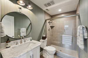 Full bathroom featuring visible vents, toilet, a shower stall, and vanity