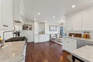 Kitchen featuring stainless steel dishwasher, tasteful backsplash, white cabinetry, and dark wood finished floors