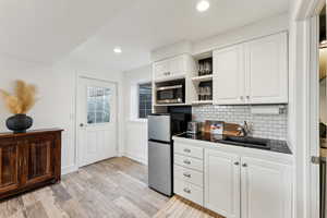 Kitchen with tile countertops, open shelves, white cabinets, a sink, and stainless steel appliances