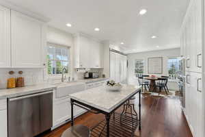 Kitchen featuring plenty of natural light, built in appliances, white cabinetry, and a sink