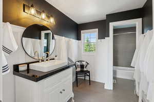 Full bathroom with bathtub / shower combination, vanity, and wainscoting