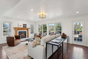 Living room with dark wood-type flooring, recessed lighting, plenty of natural light, and a glass covered fireplace