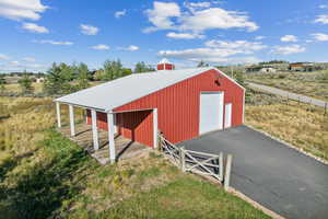 View of pole building with driveway and fence