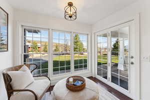 Sunroom with french doors, a notable chandelier, and wood finished floors