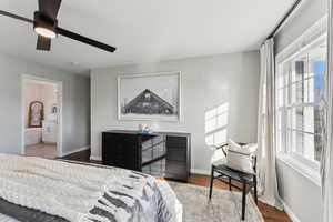 Bedroom featuring ceiling fan, ensuite bathroom, baseboards, and wood finished floors
