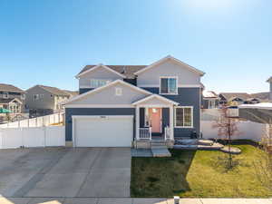 Traditional-style home featuring stucco siding, driveway, an attached garage, a front yard, and fence