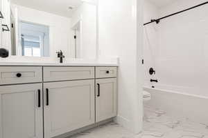 Full bath featuring marble finish floors, vanity, and tub / shower combination