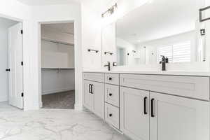 Bathroom featuring double vanity, a shower stall, marble finish floors, and a walk in closet