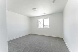 Carpeted empty room with a textured ceiling and a smoke detector