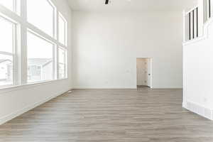 Unfurnished room with ceiling fan, a high ceiling, and light wood-style floors