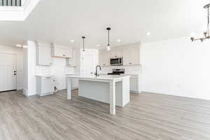 Kitchen featuring stainless steel appliances, a chandelier, tasteful backsplash, light countertops, and recessed lighting