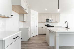 Kitchen featuring stainless steel appliances, tasteful backsplash, pendant lighting, recessed lighting, and light wood-type flooring