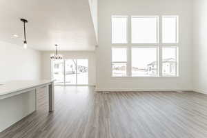 Unfurnished living room with a chandelier, light wood-type flooring, and a textured ceiling