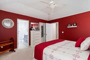 Primary bedroom with ensuite bathroom, walk-in closet, baseboards, a ceiling fan, and carpet