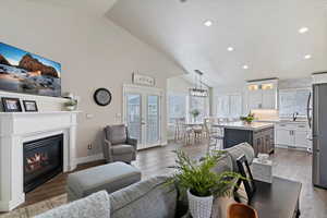 Great room featuring a gas log fireplace, baseboards, recessed lighting, high vaulted ceiling, and LVP flooring