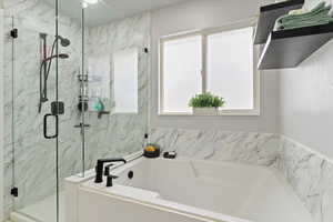 Remodeled primary en suite with a soaking bath, a marble finish shower, and lots of natural light