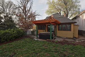 Back of house featuring a pergola, a hot tub, a yard, fence, and a chimney