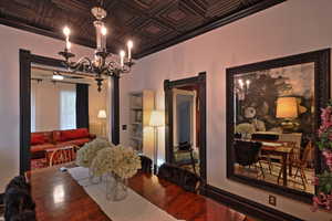 Dining room featuring a notable chandelier, an ornate ceiling, crown molding, and wood finished floors