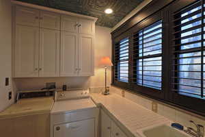 Washroom with cabinet space, an ornate ceiling, separate washer and dryer, and a sink