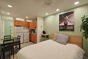 Apartment with freestanding refrigerator, light tile patterned floors, and recessed lighting