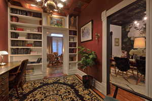 Office space with wood finished floors, a notable chandelier, built in shelves, and baseboards