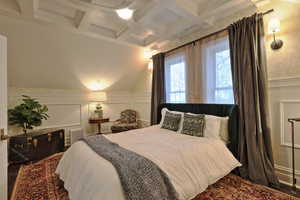 Bedroom with a decorative wall, ornamental molding, beam ceiling, a wainscoted wall, and coffered ceiling