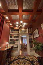 Office featuring built in shelves, a notable chandelier, beamed ceiling, and coffered ceiling