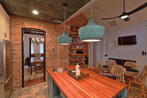 Dining area featuring brick wall, ceiling fan with notable chandelier.