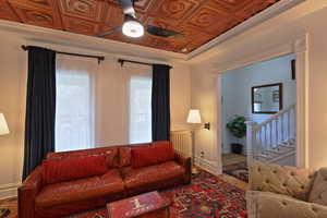 Living room with ceiling fan, wood finished floors, stairs, an ornate ceiling, and radiator heating unit