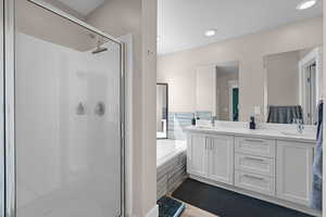 Primary bathroom with separate tub and shower, dual sinks, and a large walk-in closet