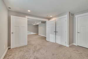 Below grade area featuring visible vents and light colored carpet