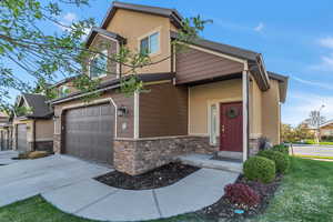 View of front of property featuring concrete driveway, stone siding, and stucco siding