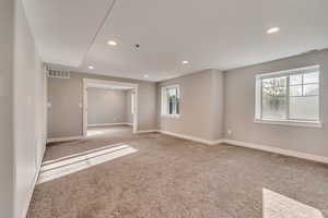 Empty room with light colored carpet, baseboards, visible vents, and recessed lighting