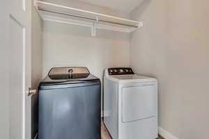 Laundry room featuring laundry area, washing machine and clothes dryer, and wood finished floors