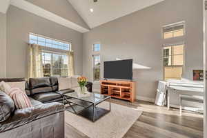 Living room featuring wood finished floors, high vaulted ceiling, baseboards, and recessed lighting