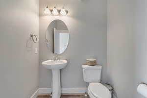 Bathroom featuring a sink, toilet, wood finished floors, and baseboards