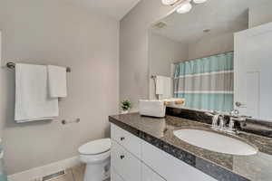 Bathroom with toilet, tile patterned floors, vanity, and visible vents