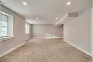 Below grade area with visible vents, baseboards, recessed lighting, and carpet flooring