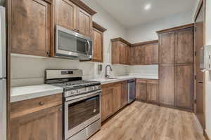Kitchen with a sink, recessed lighting, appliances with stainless steel finishes, and light wood-style floors