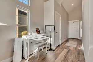 Interior space featuring baseboards, high vaulted ceiling, and wood finished floors