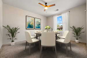 Carpeted dining area with visible vents, baseboards, and ceiling fan